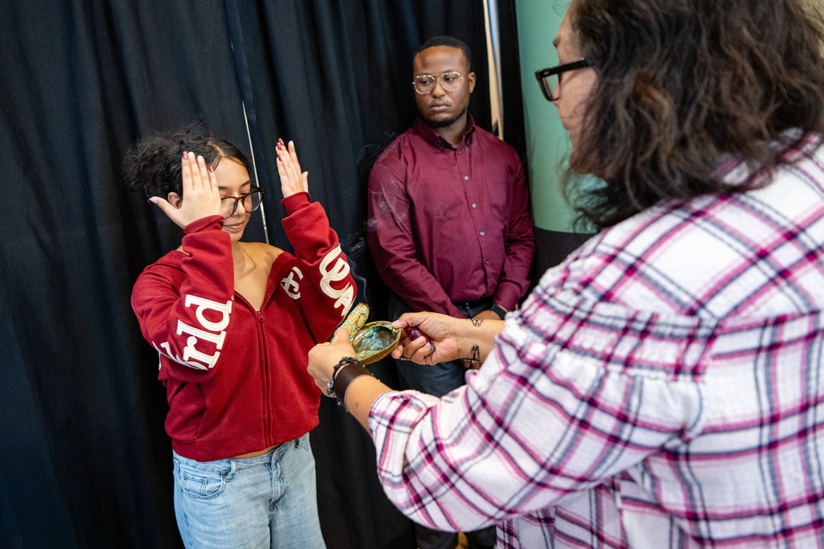 A person performs a smudging ceremony at the Indigenous Peoples' Day Celebration.