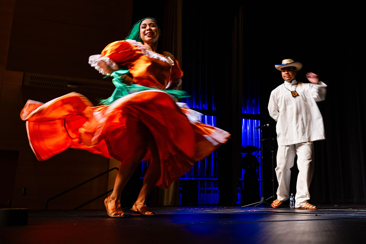 A dancer in a colorful dress spins on a stage.