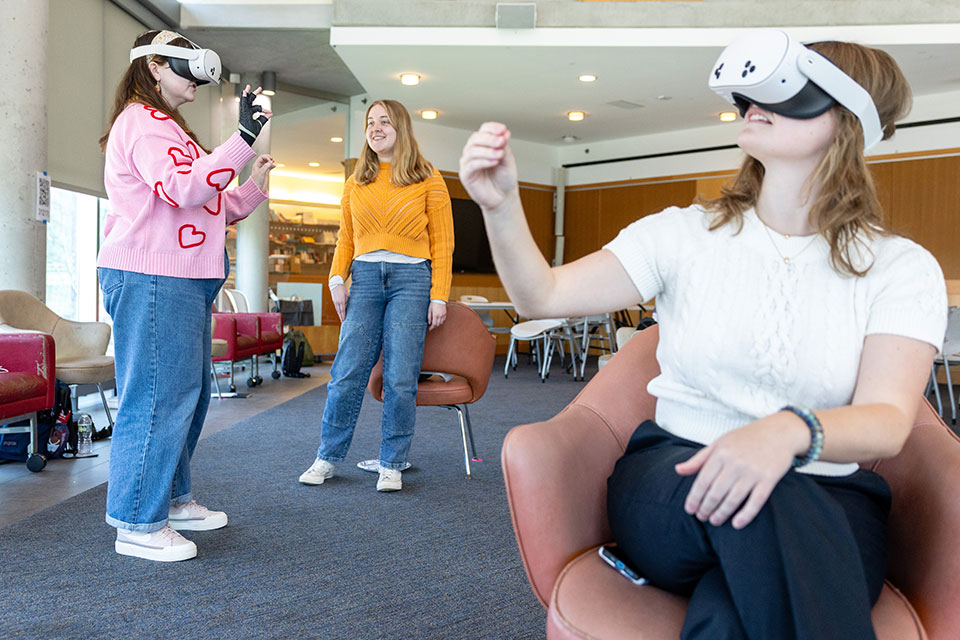 Three students in a classroom using virtual reality headsets.