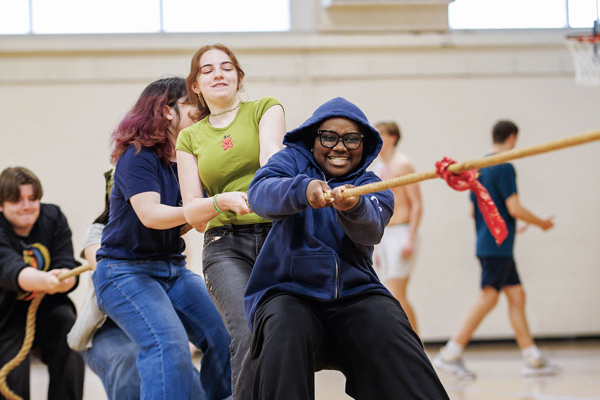 Students dressed in their quad colors play a game of tug of war.