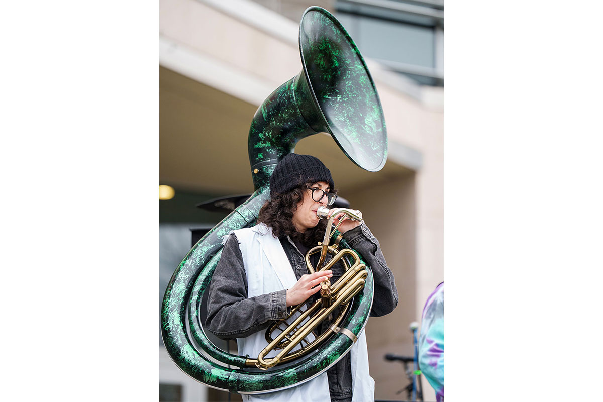 A musician play a large green trombone.