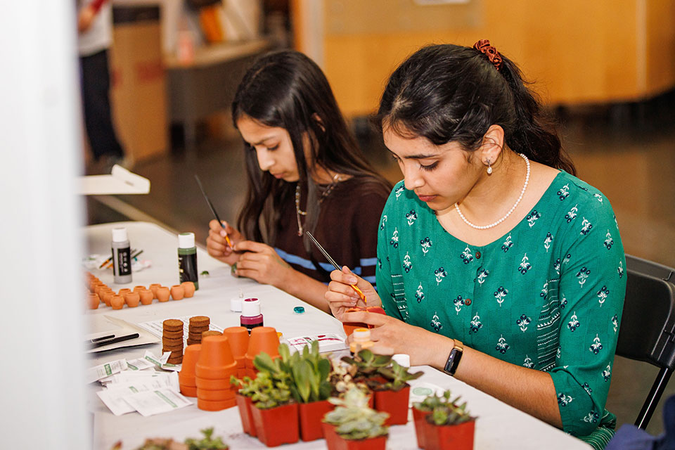 Two students paint plant pots at Vaisakhi.