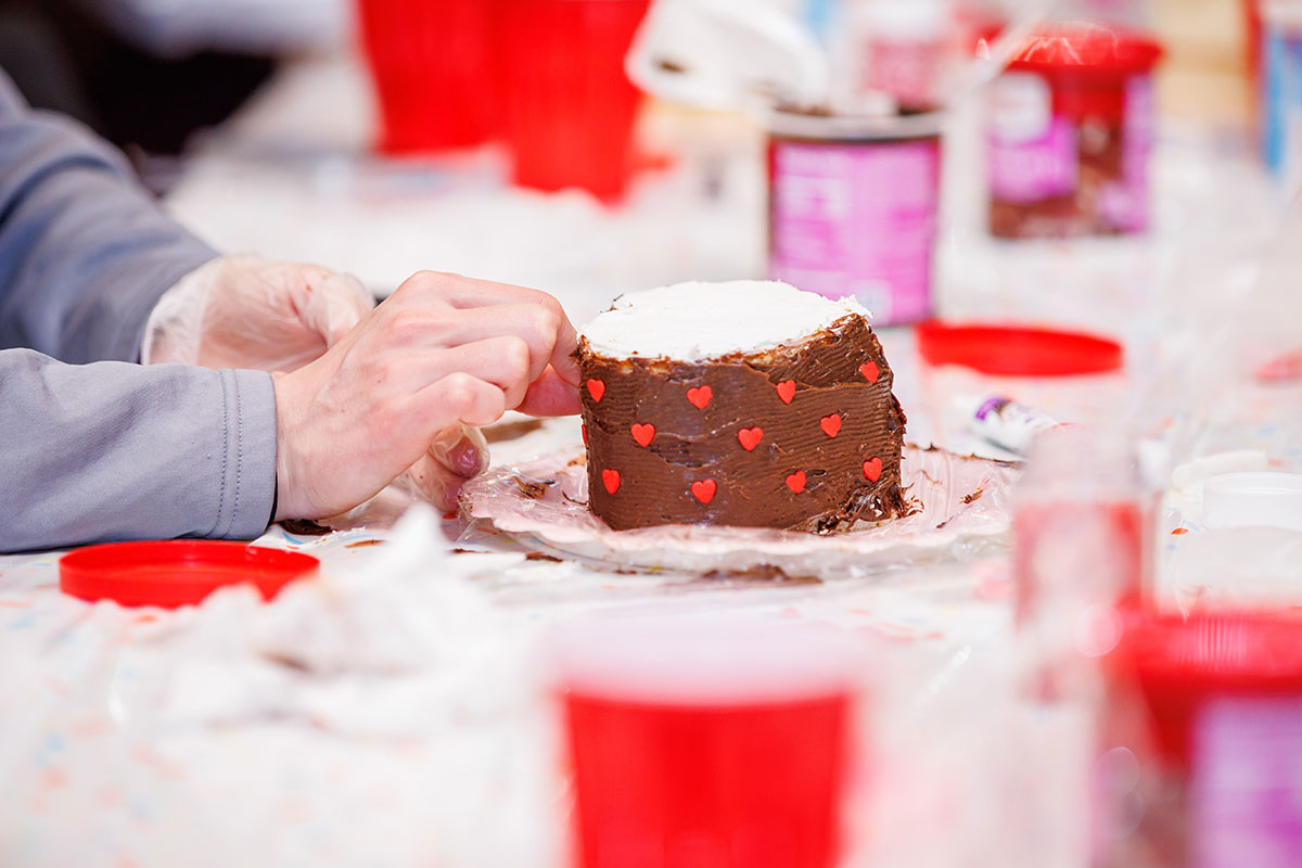 A mini cake covered with chocolate frosting and red hearts.
