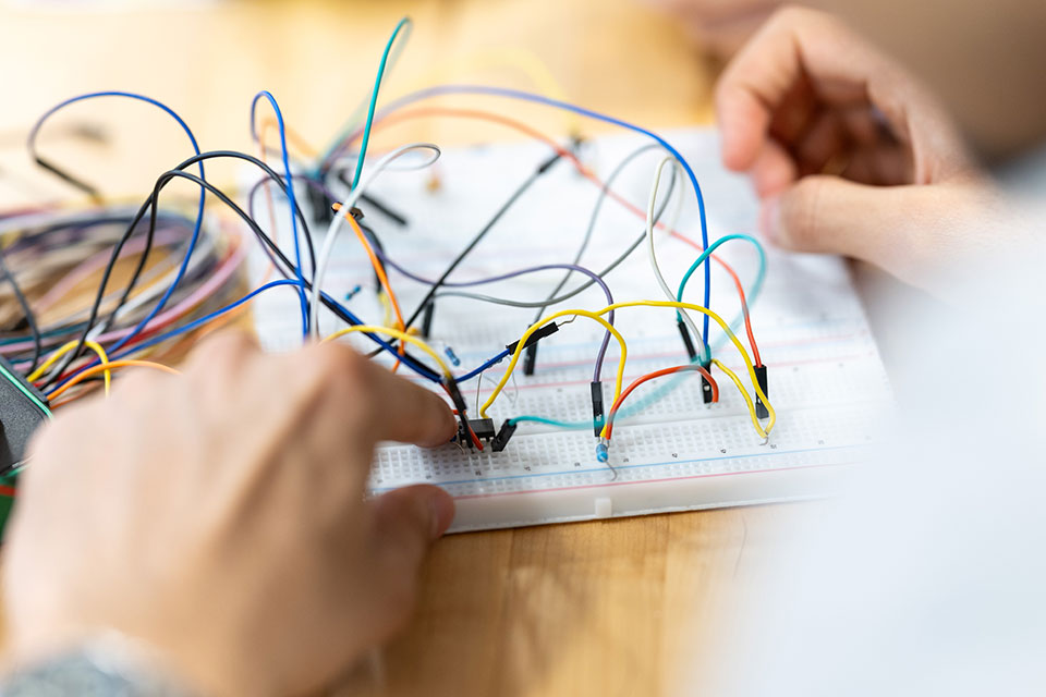 A close-up view of an engineering student's hands working with wires.