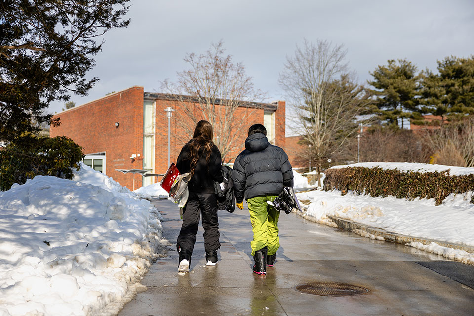 Two students walk together on a snowy day on campus.