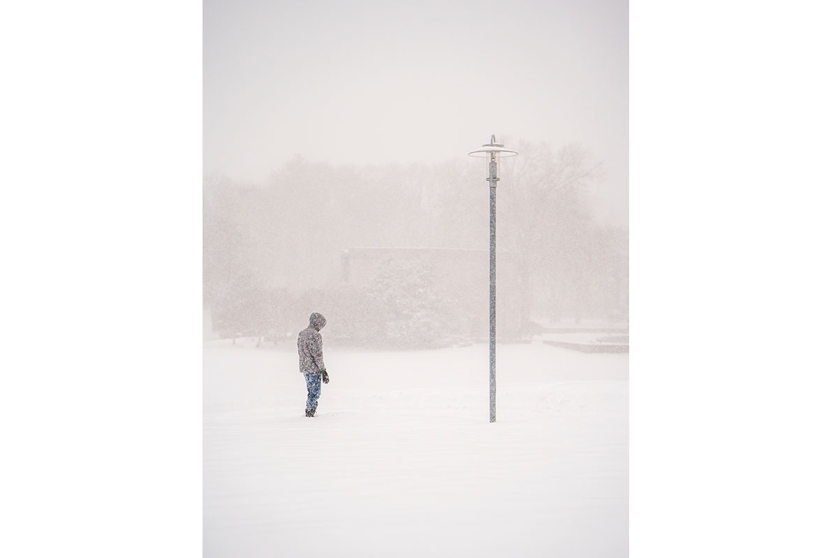 A student stands on campus in a blizzard.