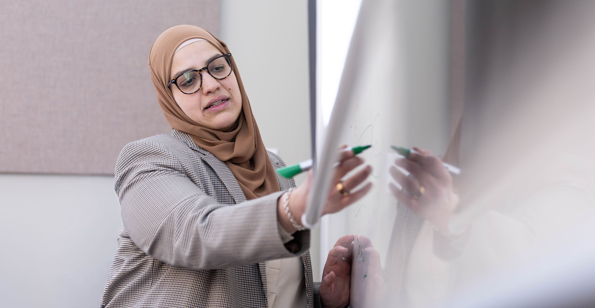 A professor writes on a white board.