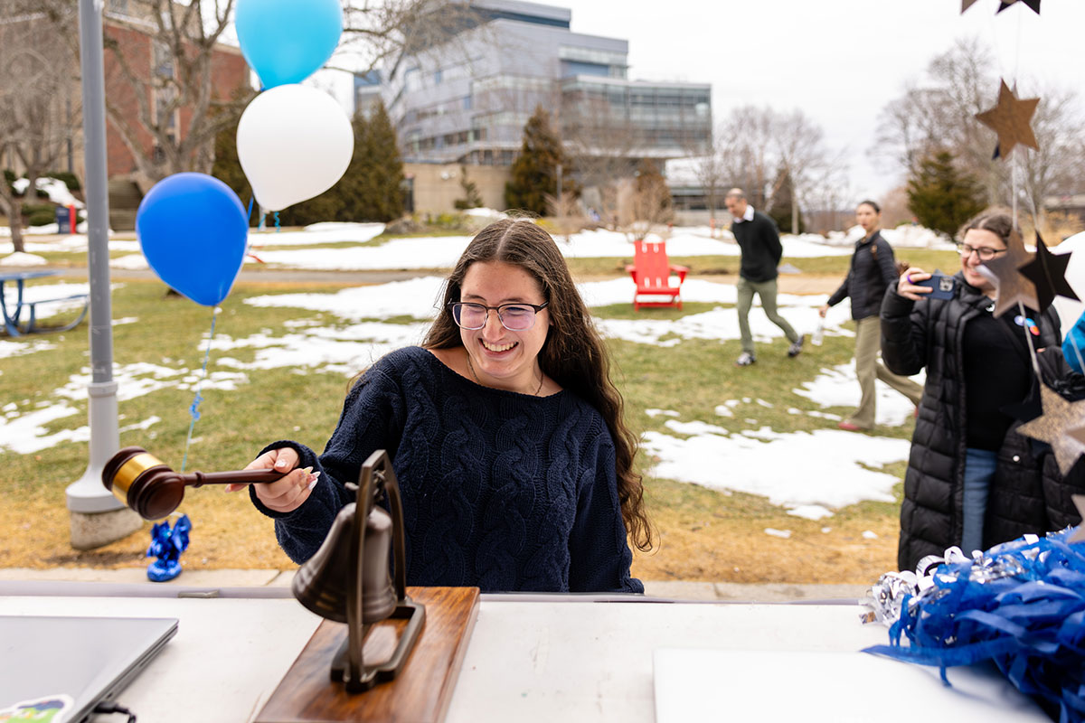 An admitted student rings a bell at Inside 'Deis Day, signifying their enrollment at Brandeis.