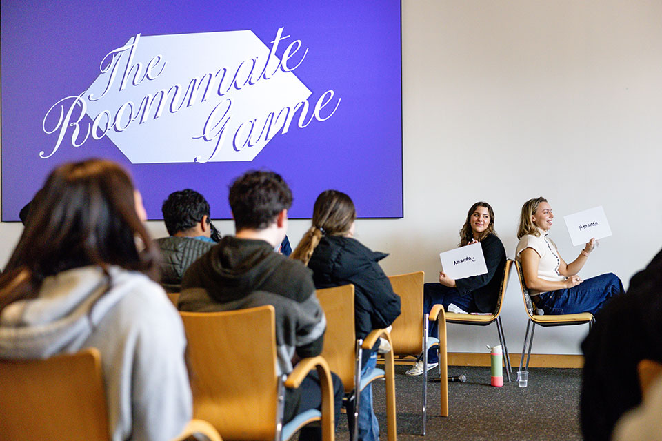 Students sit back-to-back in chairs during a game on Inside Deis Day.