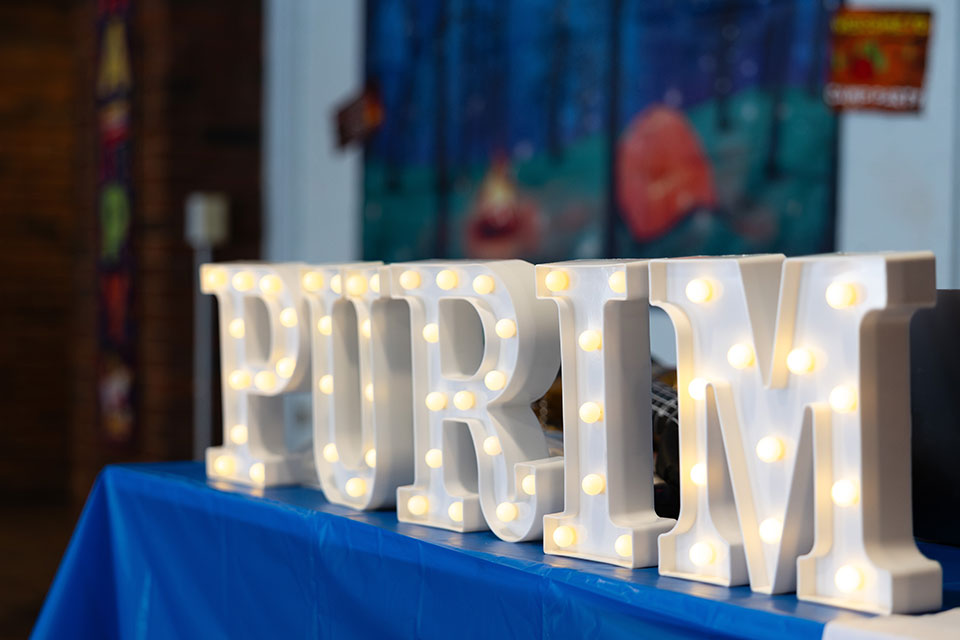 A large sign with lights that reads "Purim"
