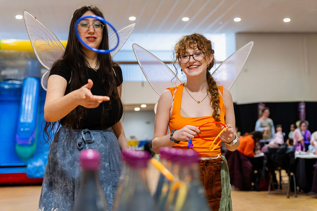 Students dressed in costumes play a ring toss game.