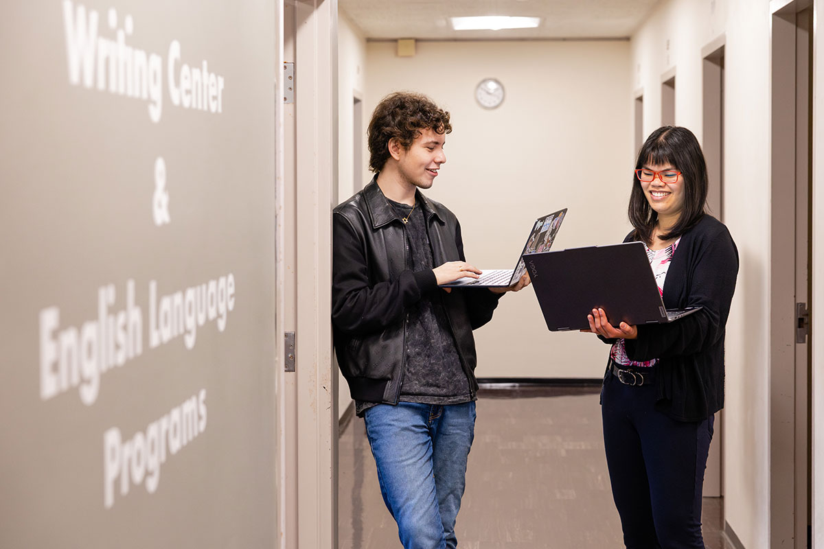Two people work on their laptops in the Brandeis Writing Center.