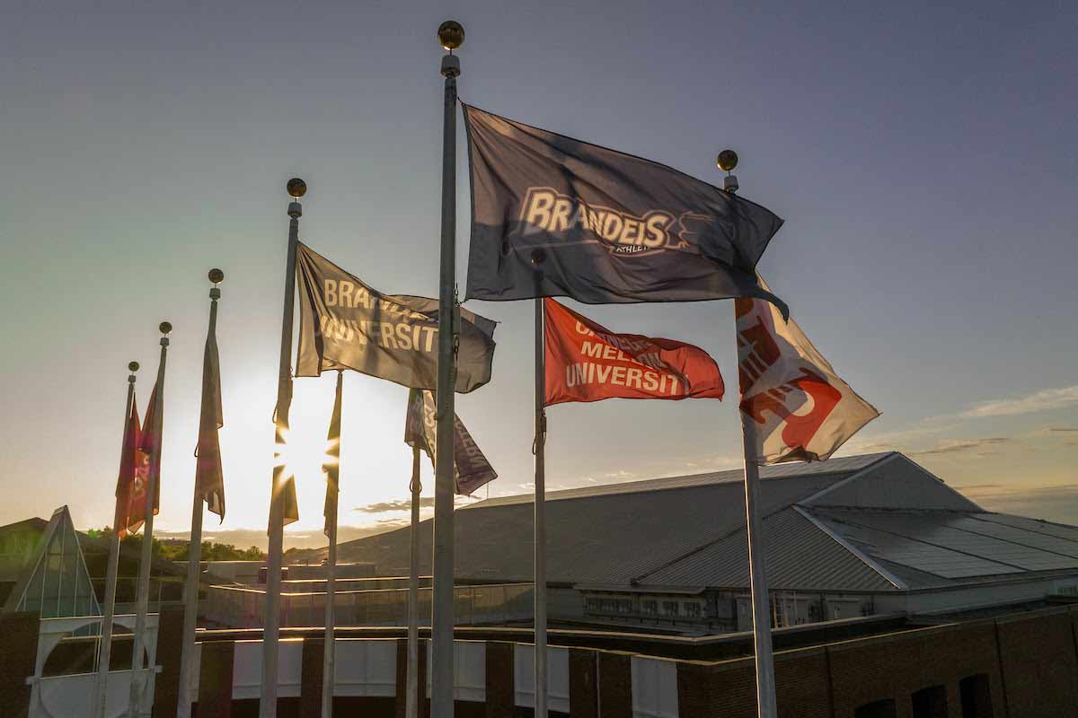 The flags at Gosman Sports and Convocation Center with the sun rising behind them. 