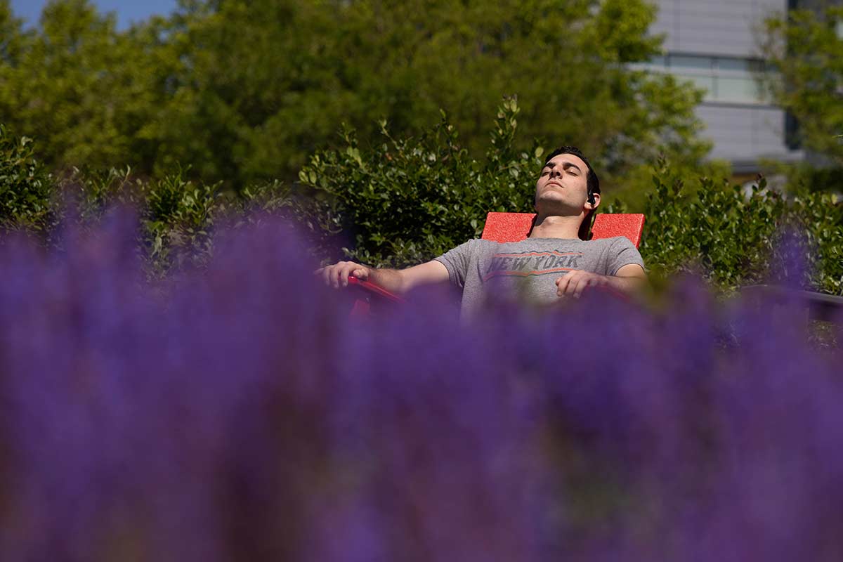 A student lays back in a chair soaking up the sun