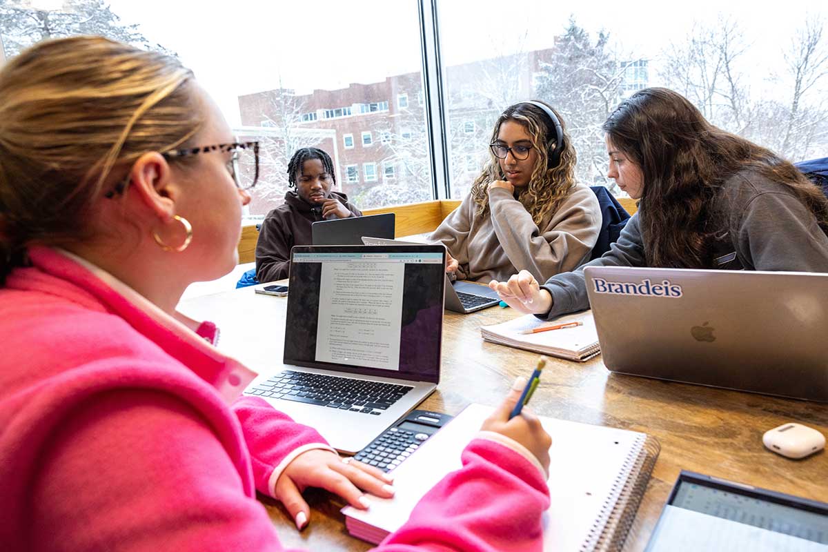 Students sitting at a table surrounded by notebooks and computers