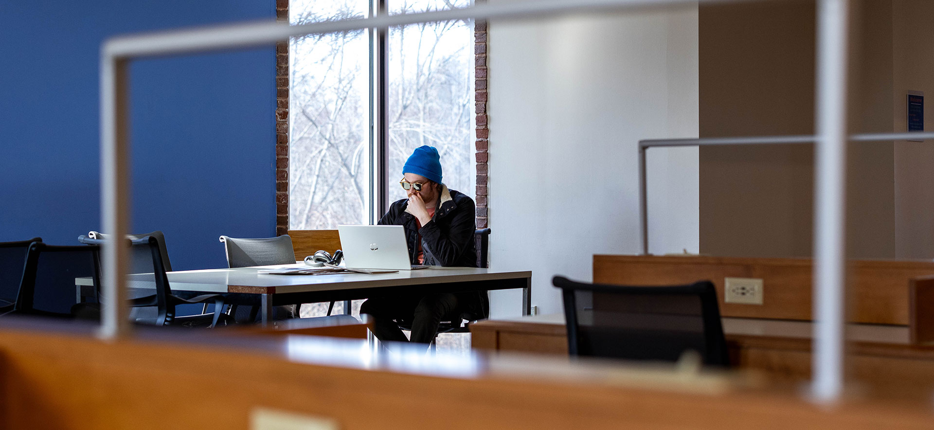 A student with sunglasses on looks at a laptop