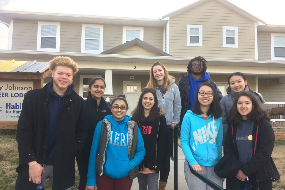 Habitat volunteers smiling in front of a built house.