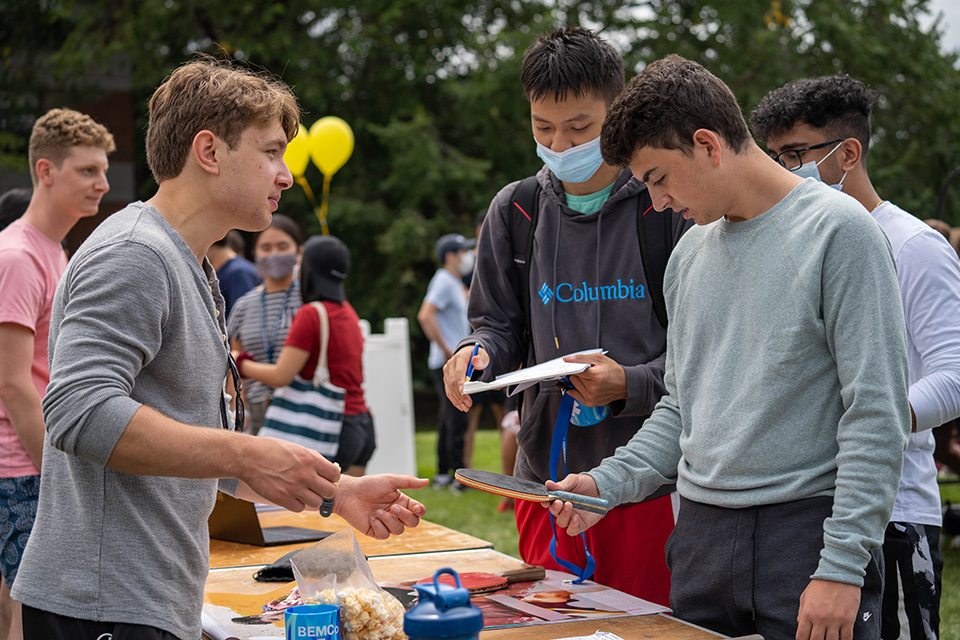 Students talking at the Involvement Fair. ONe is holding a table tennis paddle