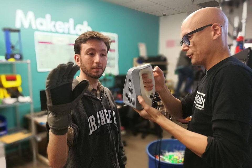 A student with a glove on his hand in the MakerLab
