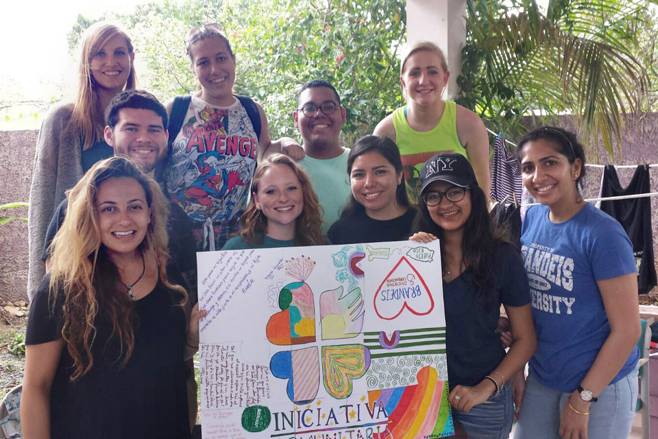 Student volunteers standing in front of a wall of recycled plastic bottles.