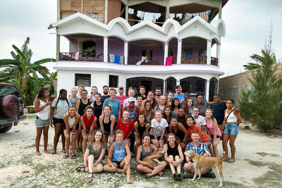 Students and a dog gathered in front of a house.