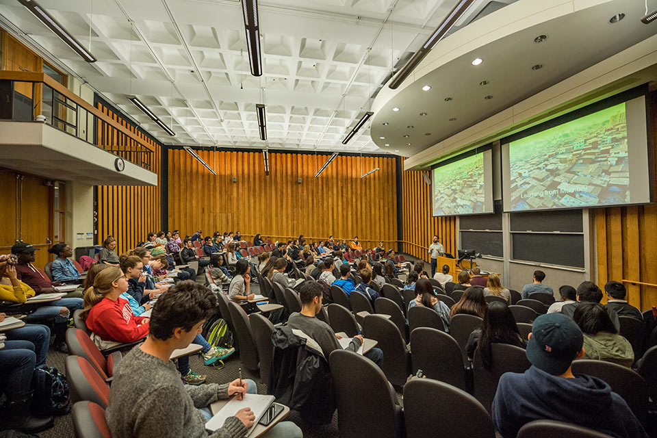 Faculty member speaking in front of a large lecture hall