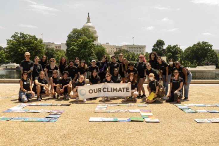 photo of people from our climate with sign that says our climate in front of national capitol