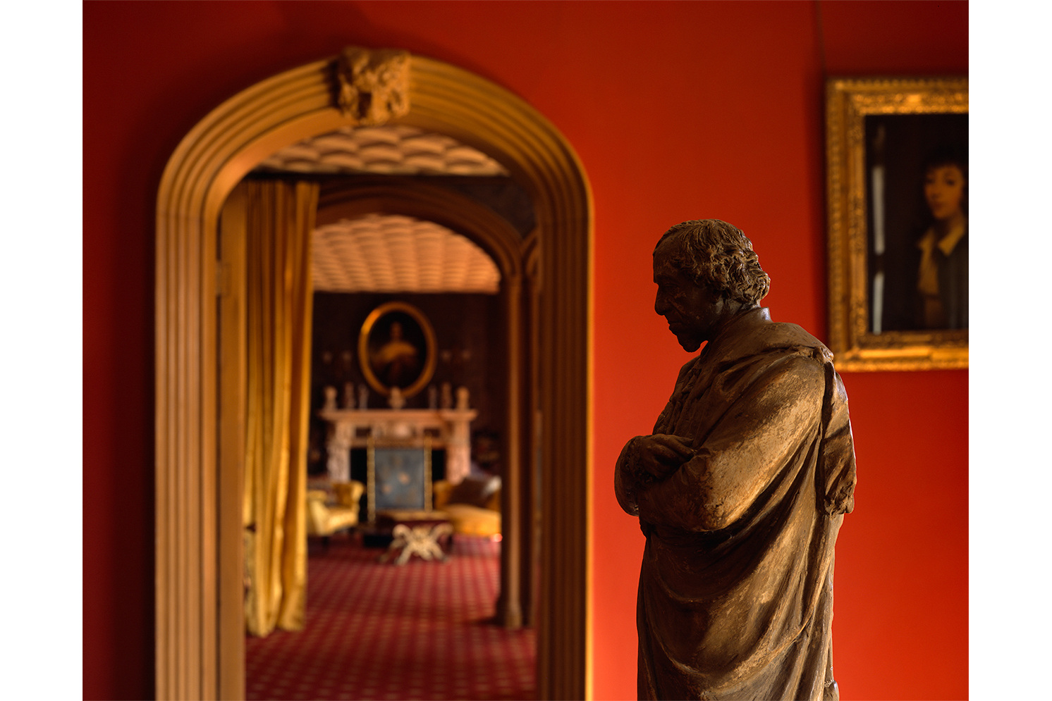 An photo made by Hélène Binet of a red and golden interior with a statue on the right side of the image