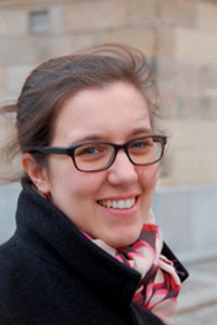 An image of Elisabeth Gallas wearing a black coat, a multicolored scarf and glasses.