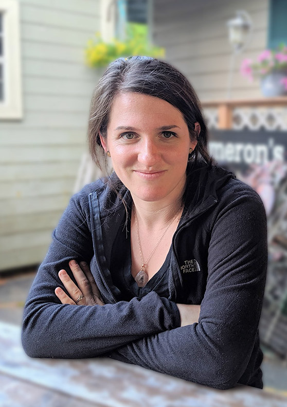 Jordan Katz seated with her arms folded outside with a house in the background