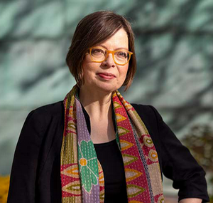 A portrait photo of Laura Jockusch wearing a scarf with the trees in the background