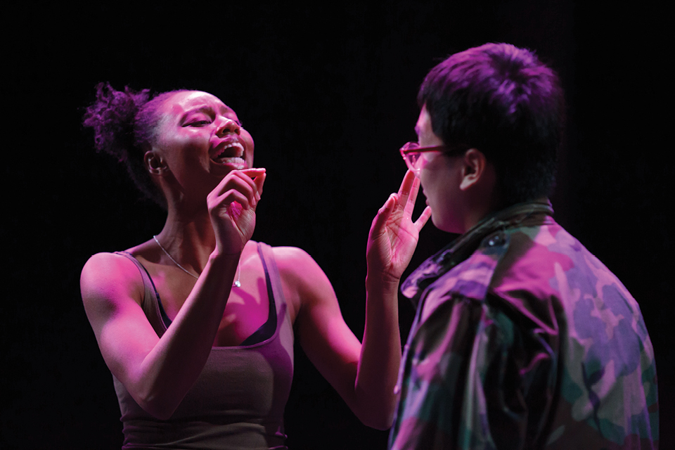 Two people in pink light, one is gesticulating to prove a point