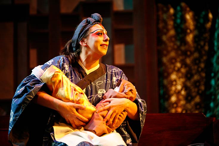 Actress holding baby with actor standing behind them performing in The Orphan of Zhao