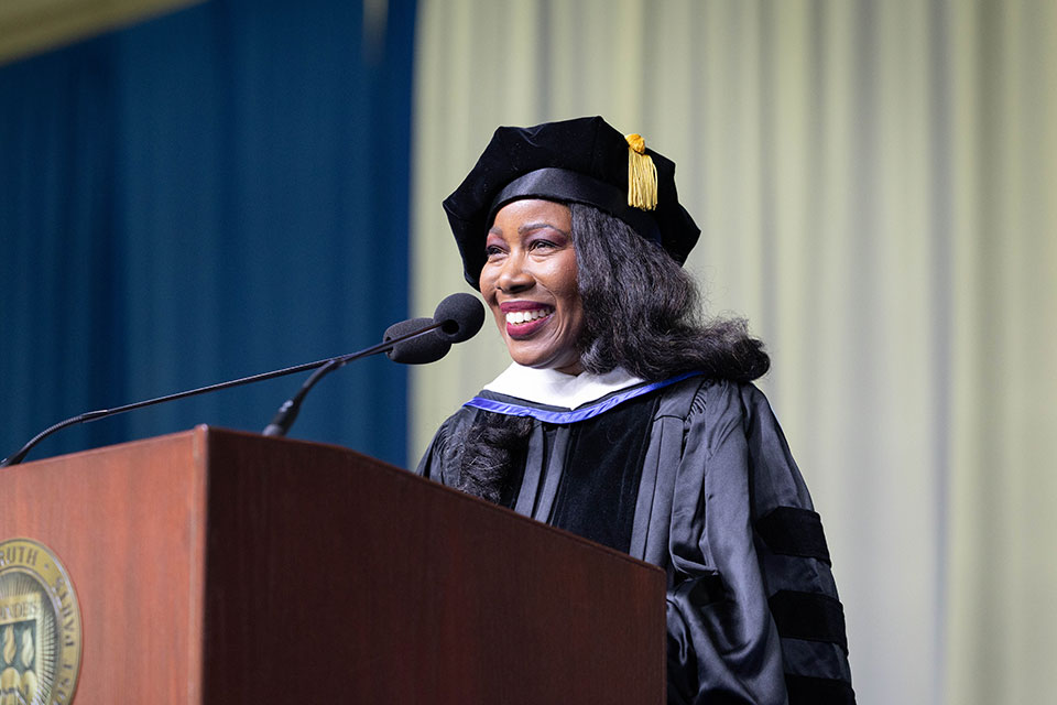Isabel Wilkerson speaking at a podium at the graduate Commencement ceremony.