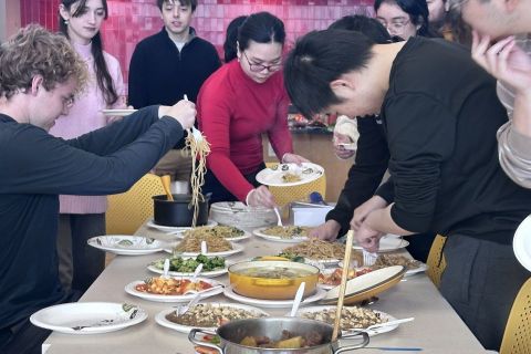 students around a table filled with Chinese food prepare their plates