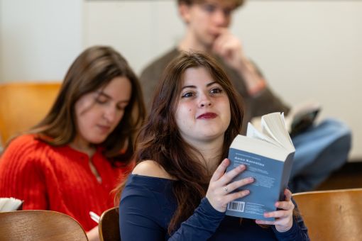 a student holds a book while listening to the professor
