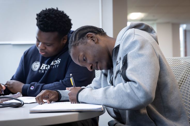 A student leaned over a desk writing in a notebook