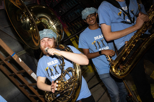 A smiling group of students play brass instruments
