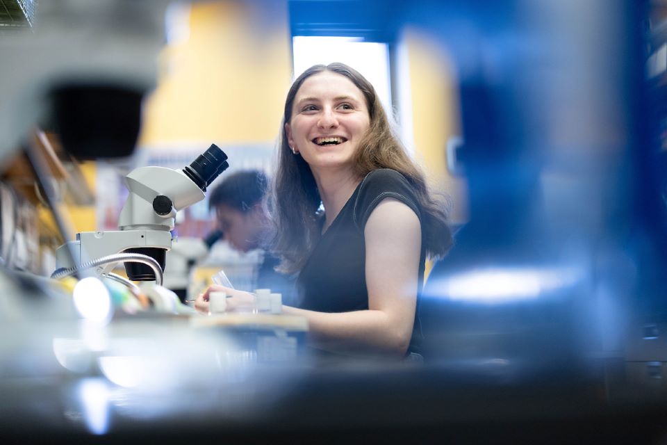 a student takes notes by a microscope