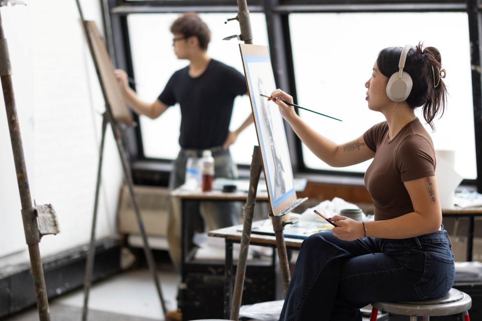 Seated students painting on canvas