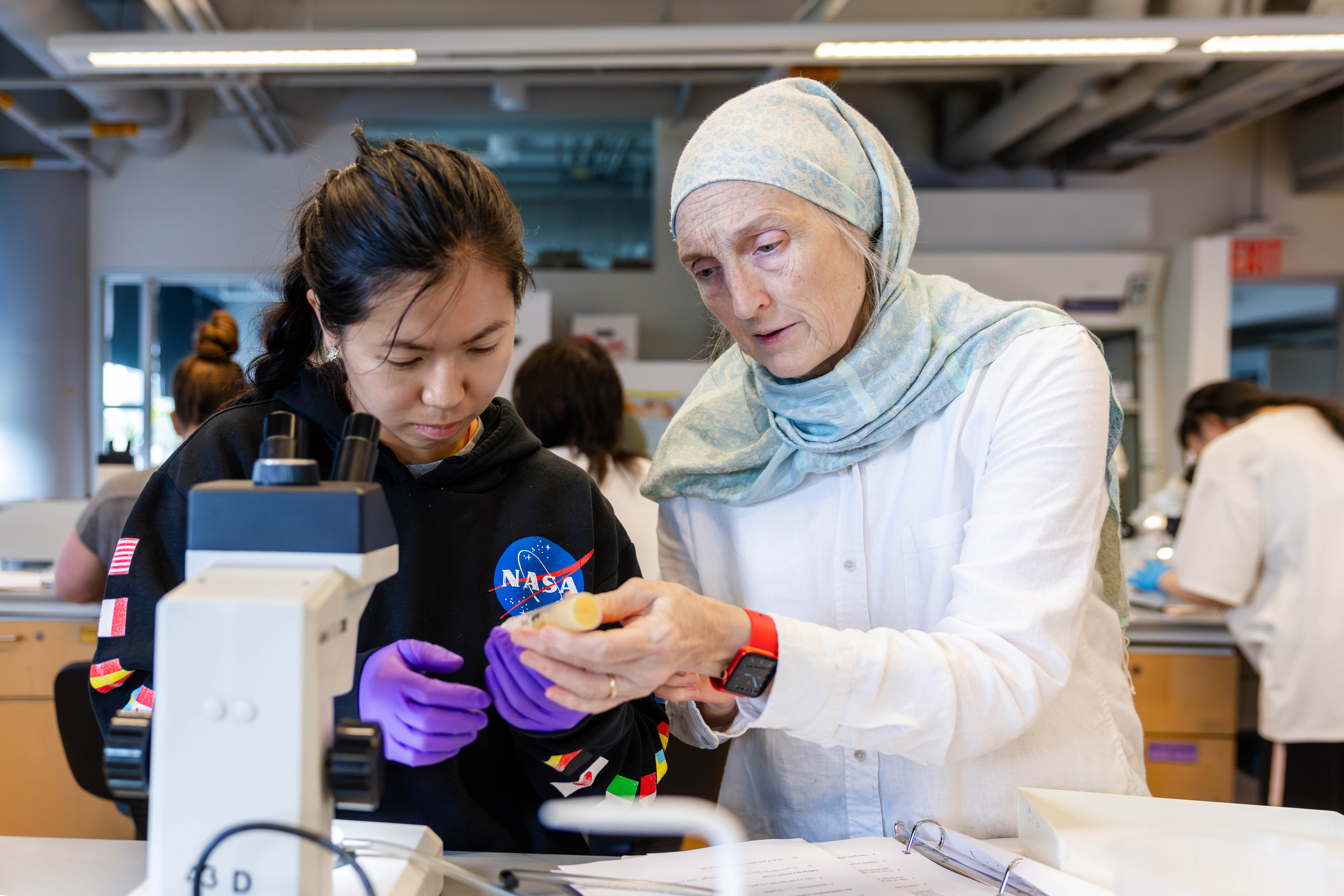 a student takes notes by a microscope