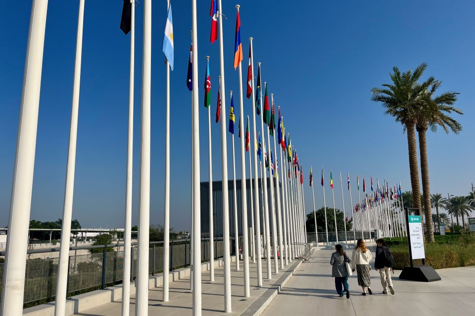 students walk past national flags in a courtyard