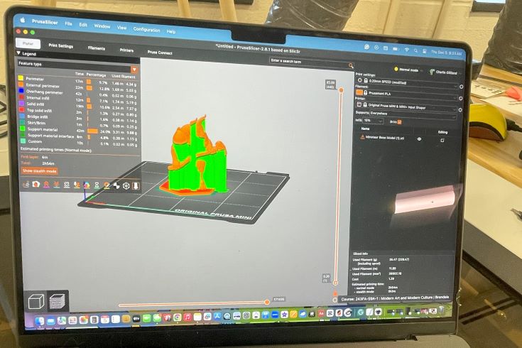 A laptop screen displays a 3D design for a game in bright green and orange coloring.