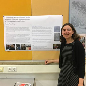 Tamar Aizenberg standing in front of research poster, smiling