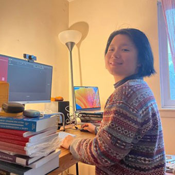 Manning Zhang sitting at a desk in front of a computer smiling