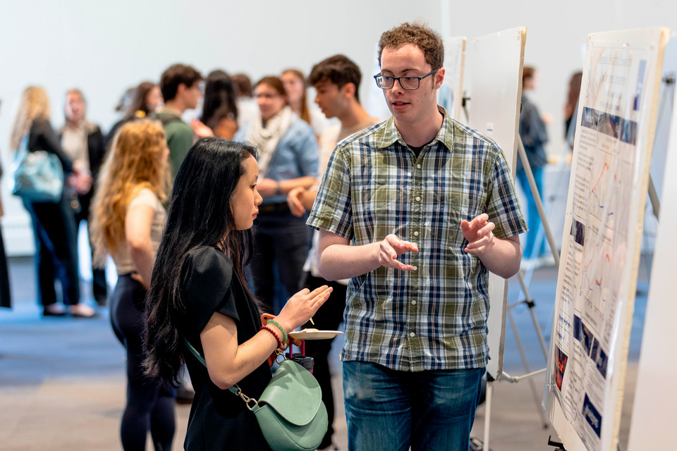 Griffin stands in front of his poster, describing his research to his peers