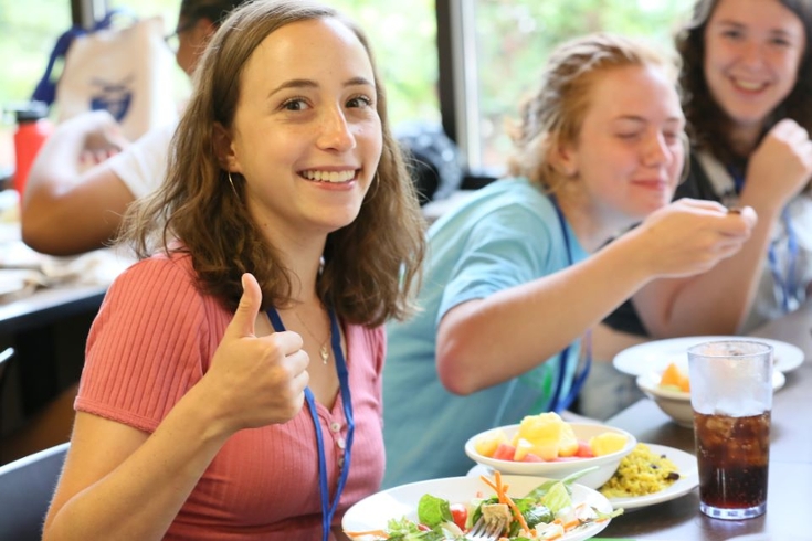 A student gives a "thumbs up" at the dining table
