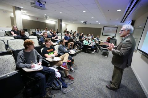 Side view of an instructor addressing a classroom with students
