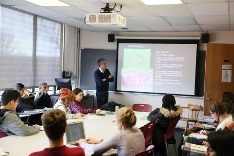 View of instructor pointing to a large visual screen