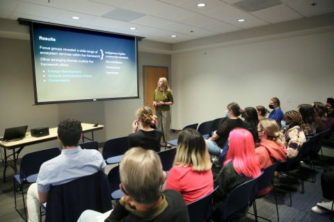 A speaker draws attention to a large visual display